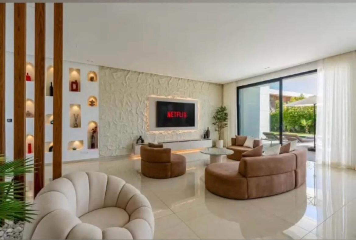 Double-height salon with sculptural seating and large smart TV at The Royal VVIP