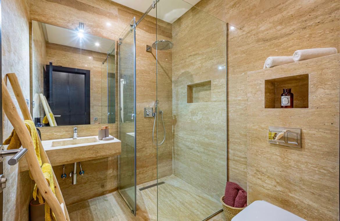 Travertine bathroom with rain shower at The Palm